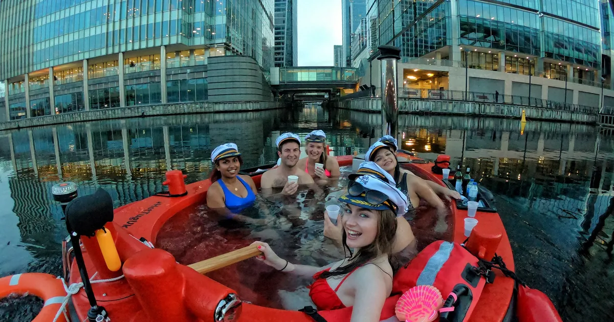 Guests in a hot tub boat on the water in the Canary Wharf docks in London