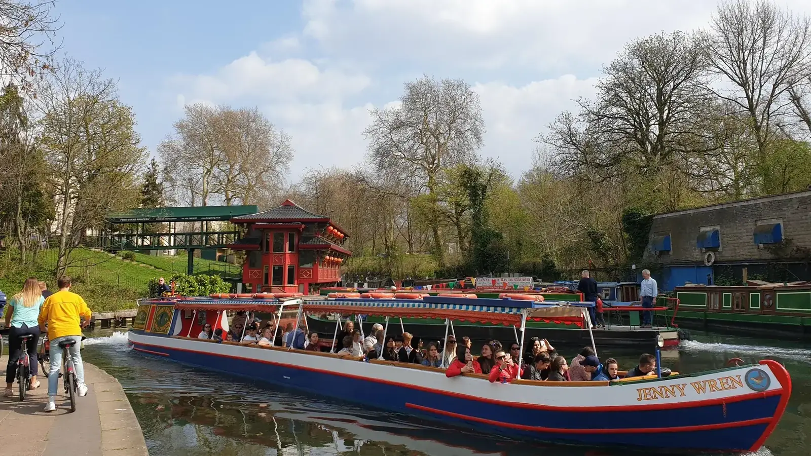 A canal boat on the Regent's Canal between green banks, from the Camden canal boat ride listing