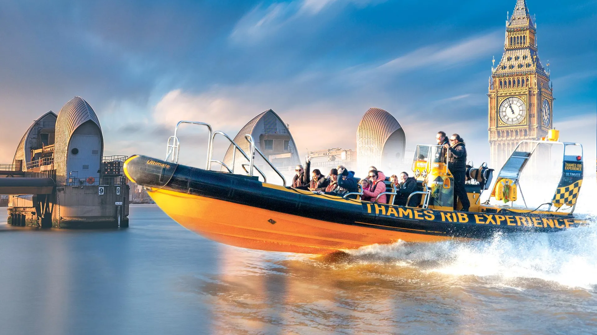 A Thames RIB speedboat on the river with the Thames Barrier and Big Ben behind, from the Thames Barrier tour listing